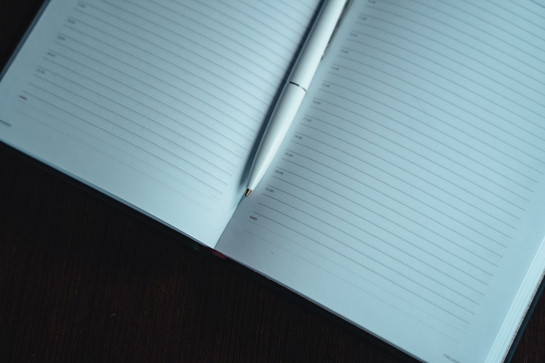 Open notebook with pen on a dark wooden table — the thoughtful planning a Hearthready plan replaces.